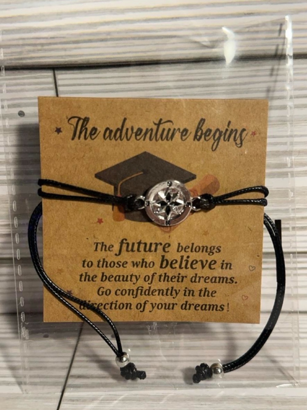 Black cord graduation bracelet with silver tone compass charm